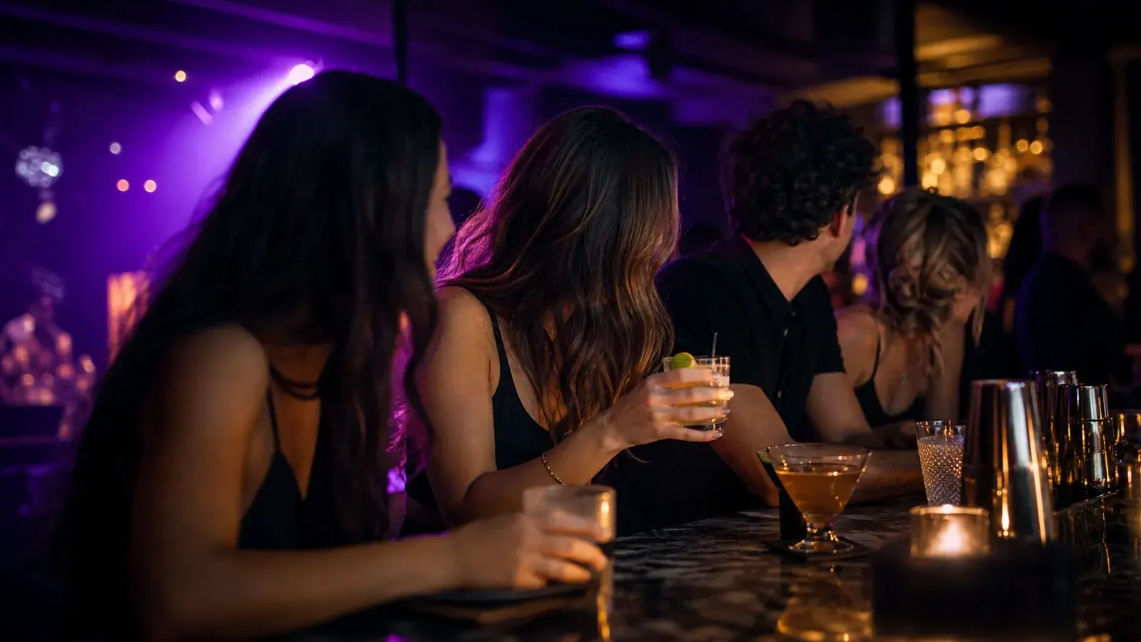 Friends enjoying a confident, safe night out at a dark upscale bar with soft purple lighting